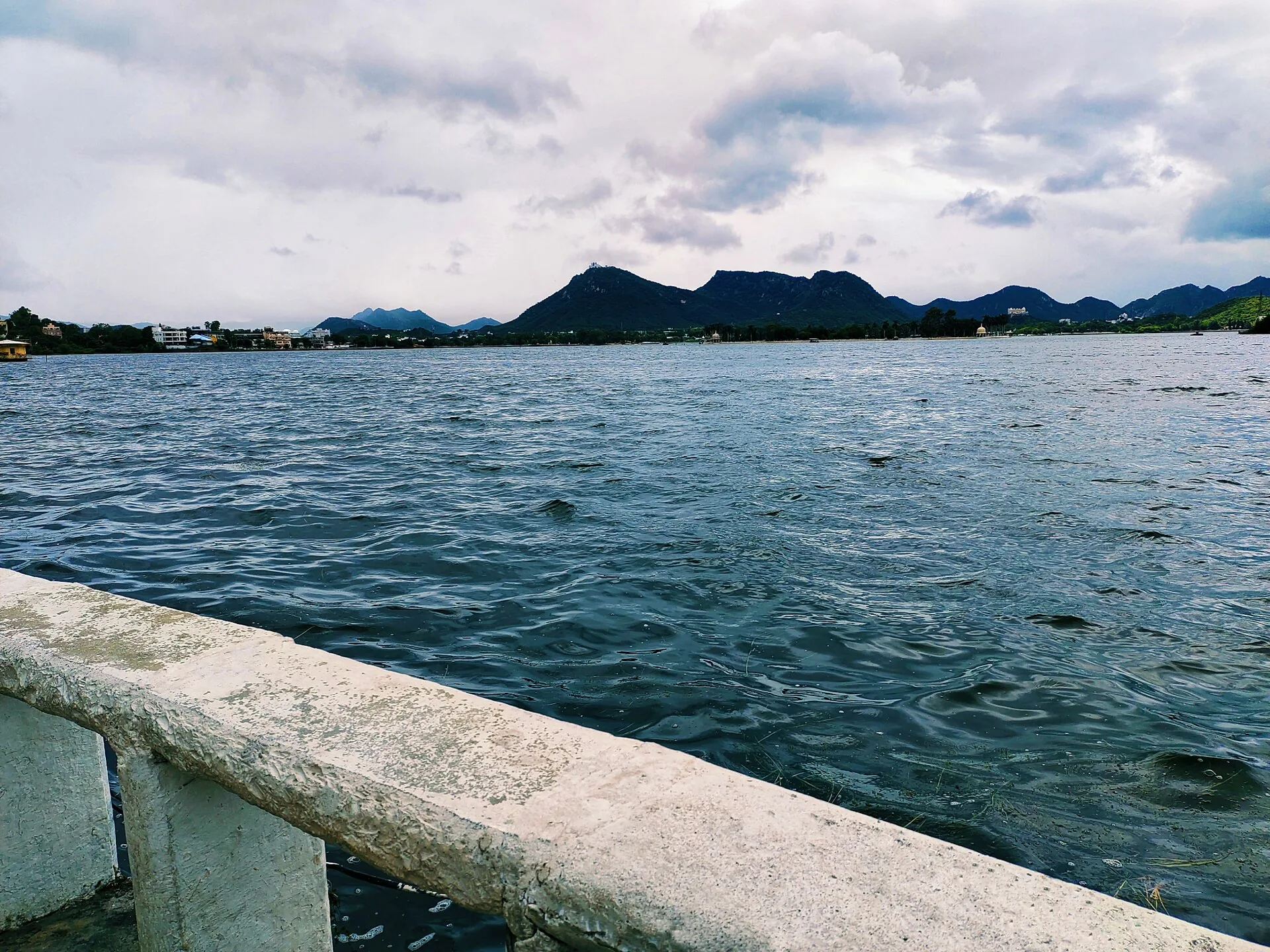 Fateh Sagar Lake with a stone lakeside railing and hills beyond